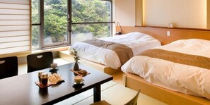 Une chambre d’hôtel avec deux lits, une table à manger avec des tasses à café, et une vue sur la verdure par la fenêtre.