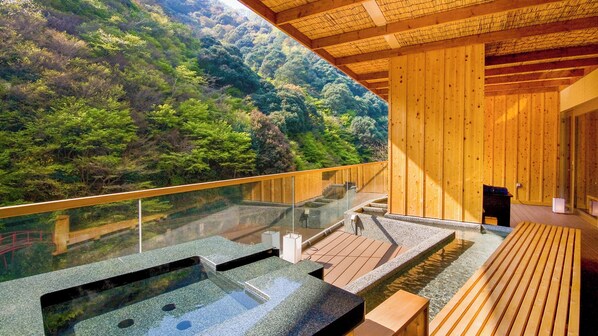 A wooden spa with a glass balustrade overlooking a forested hillside.
