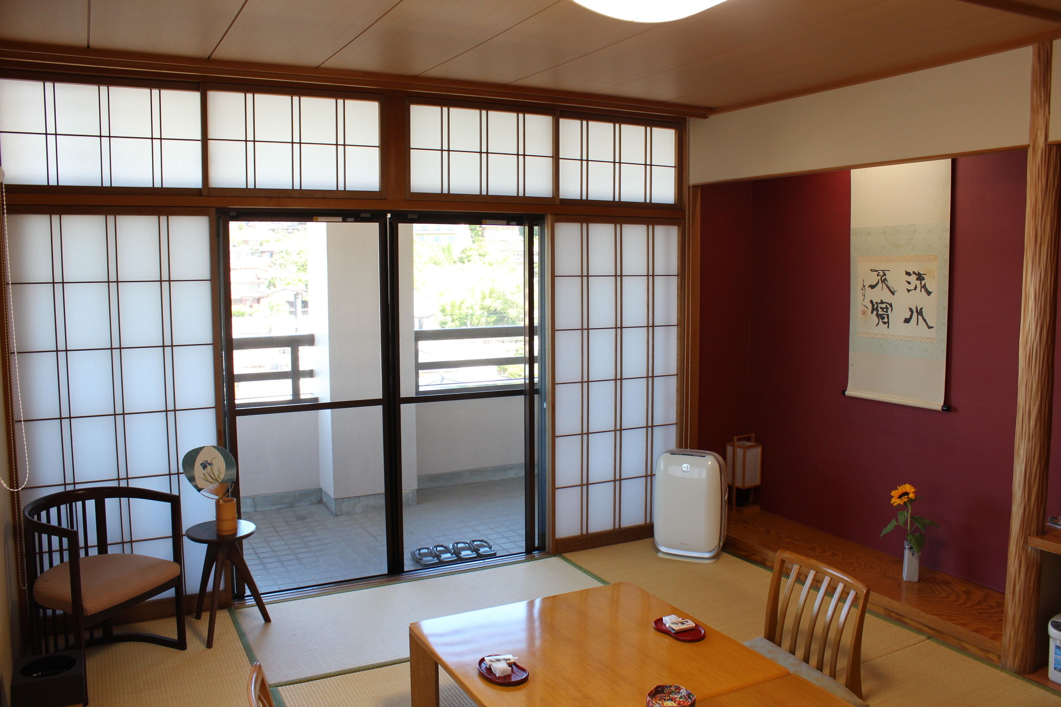Um quarto japonês tradicional com tatames, portas deslizantes e uma mesa de madeira com cadeiras.