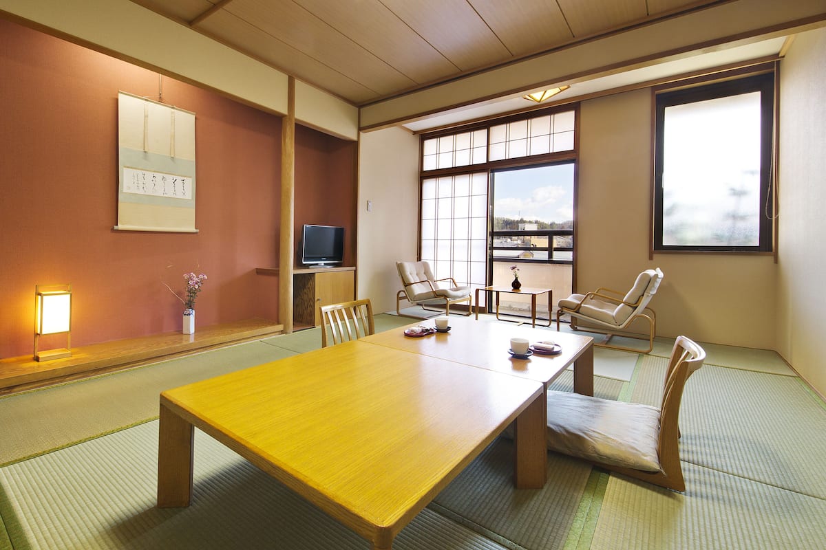 Una habitación japonesa tradicional con suelo de tatami, una mesa de madera y cuatro sillas en tatami.