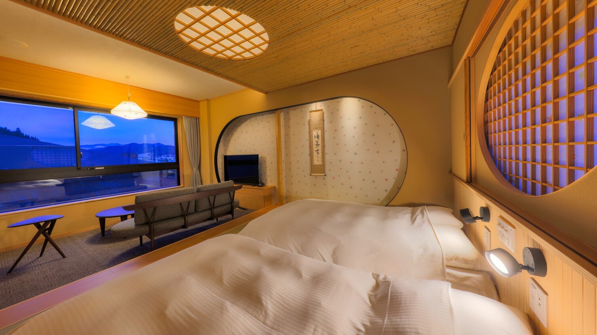 Habitación de hotel con cama, escritorio, silla, televisor, ventana y vista decorativa.