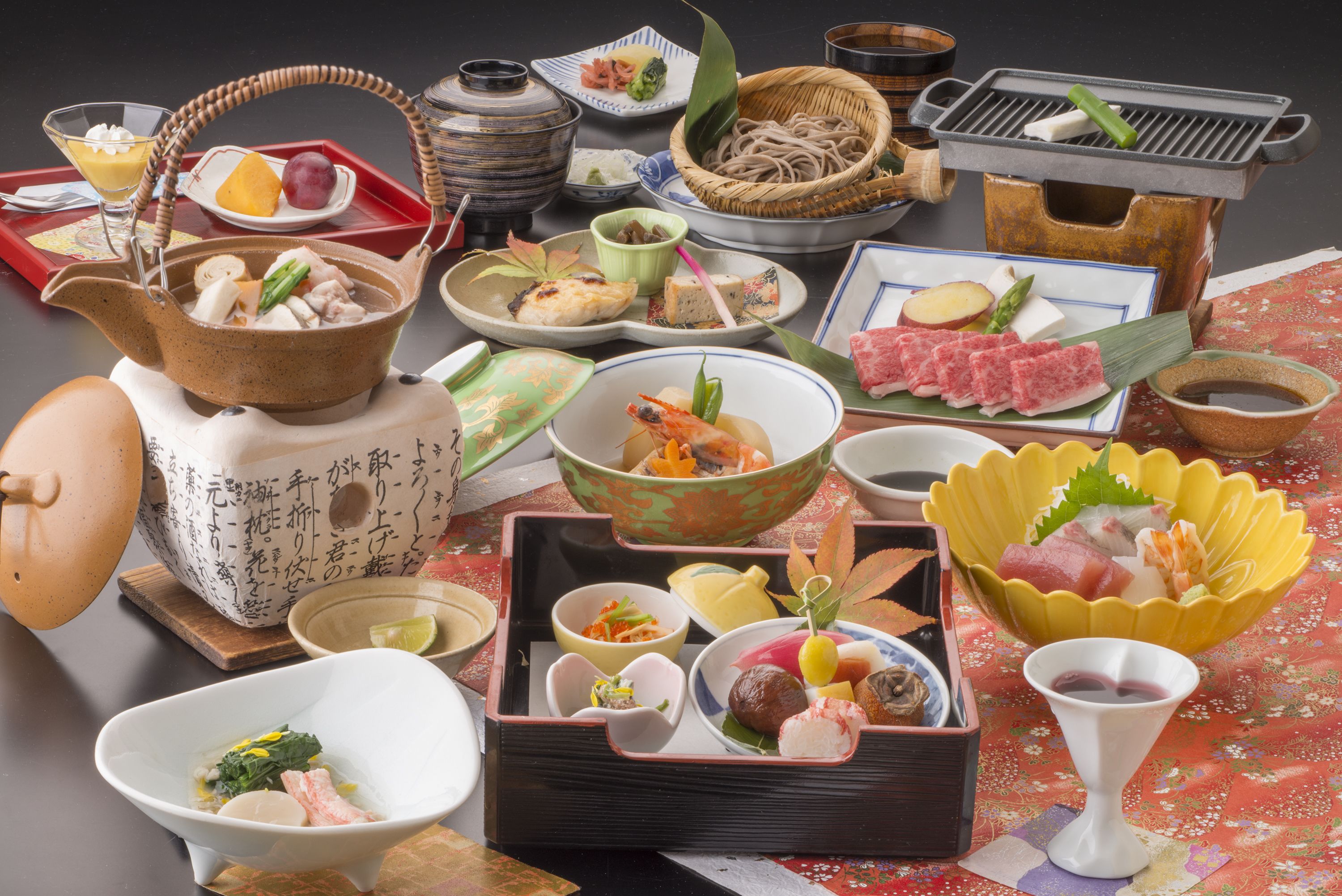 A variety of traditional Japanese dishes arranged on a table, including a teapot, bowls, and plates with food items.