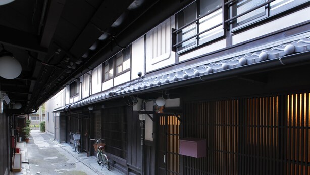 A traditional Japanese building with a tiled roof, a bicycle parked outside, and a potted plant. - Gagakuan (Kyoto)