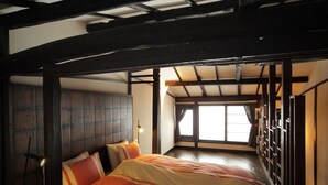 A traditional Japanese-style bedroom with tatami flooring, a low wooden bed frame, and a sliding door leading to a balcony. - Gagakuan (Kyoto)