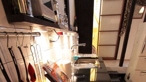 A modern kitchen with a black countertop, stainless steel appliances, and a red coffee maker. - Gagakuan (Kyoto)