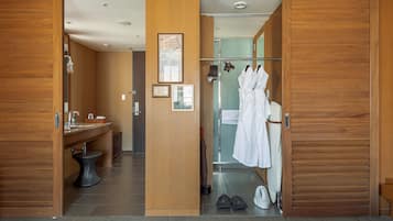 Un baño de hotel con paneles de madera, un lavamanos, un espejo y un perchero con albornoces.