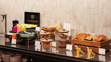 Mostrador de buffet con diversos alimentos, como frutas, pasteles y salsas.