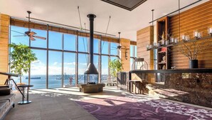 A modern hotel lobby with large windows, a fireplace, and a view of the water. - THE ORIENT (Kobe)