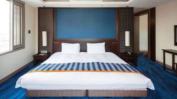 A hotel room with a large bed, a nightstand, a lamp, and a window with blinds.