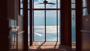 A view through a glass door leading to a balcony overlooking a body of water with a sailboat and a jet ski. - THE ORIENT (Kobe)