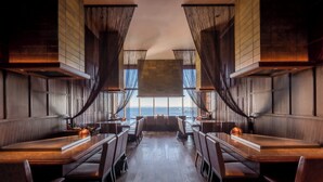 A restaurant with a long table and chairs, a view of the ocean, and wooden paneling on the walls. - THE ORIENT (Kobe)