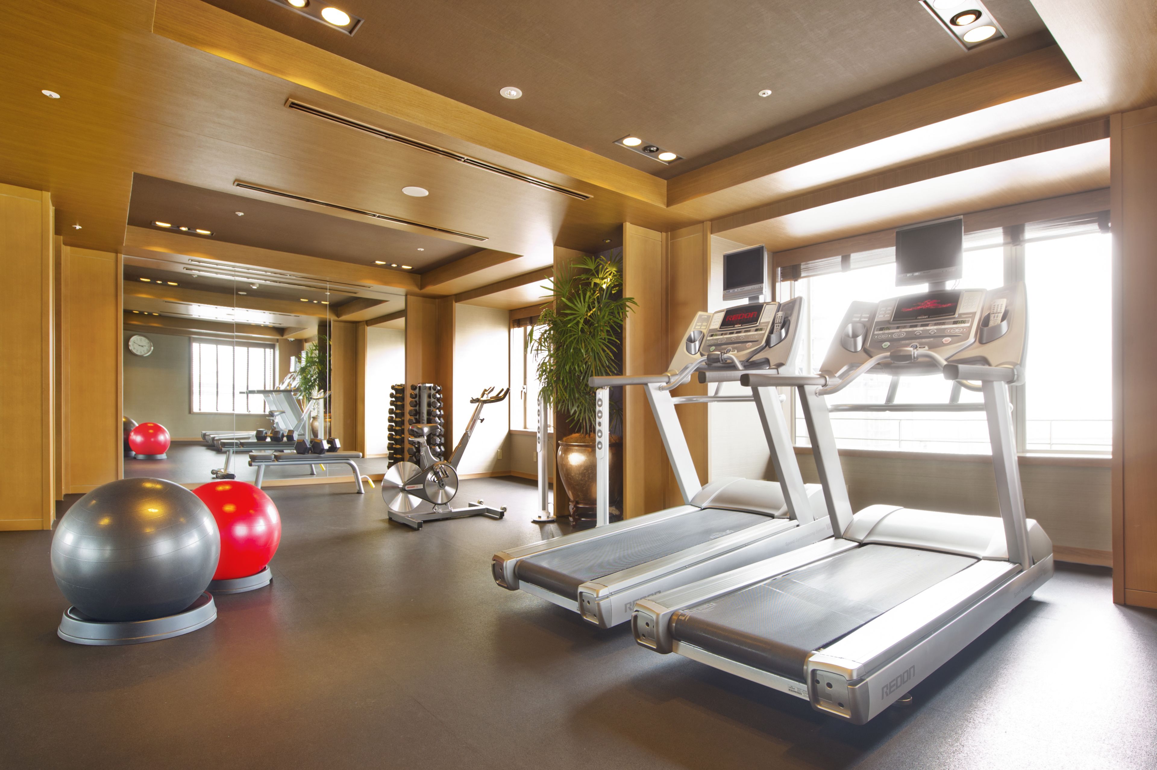 A gym with treadmills, exercise balls, and a mirrored wall.