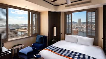 Habitación de hotel con una cama grande, un escritorio, una silla y vistas a la ciudad.