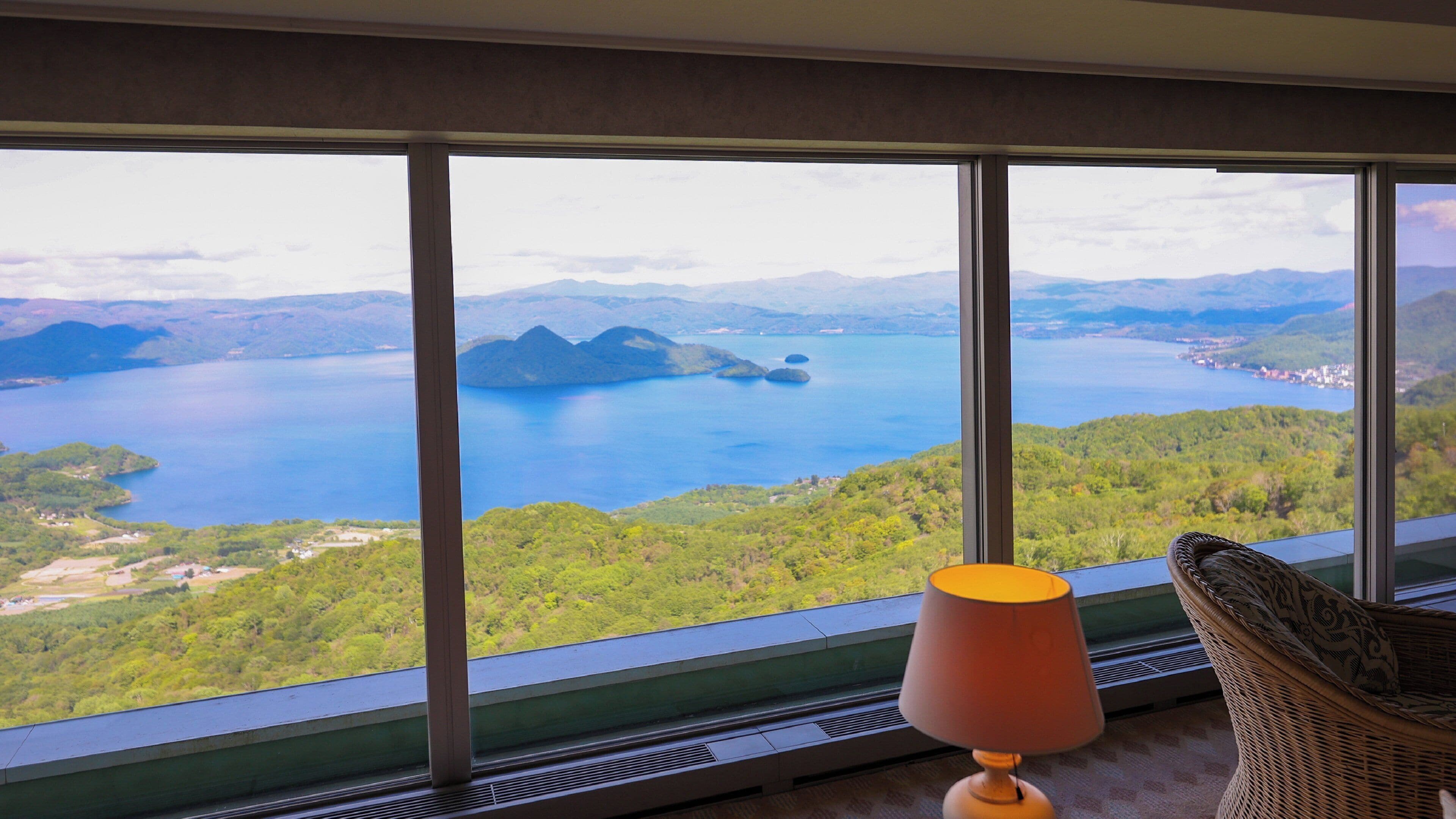 Una habitación con un amplio ventanal que ofrece vistas a un lago y montañas circundantes.