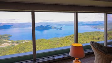 Una habitación con un amplio ventanal que ofrece vistas a un lago y montañas circundantes.