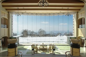 A spacious room with a large window, a chandelier, and a view of a snowy landscape. - The Windsor Hotel Toya, Vignette Collection by IHG (Toyako)