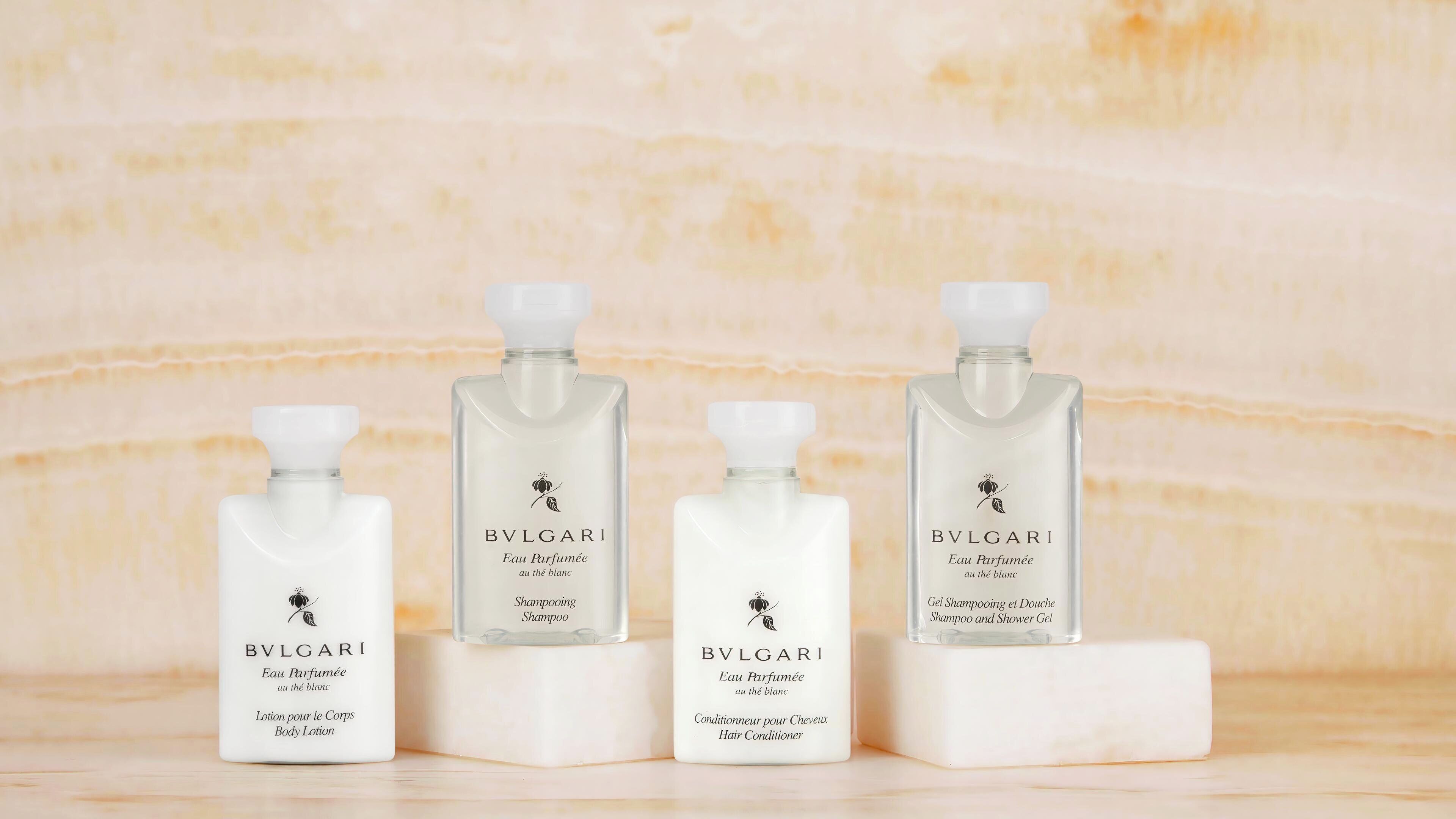 Three BVLGARI products on white marble surfaces.