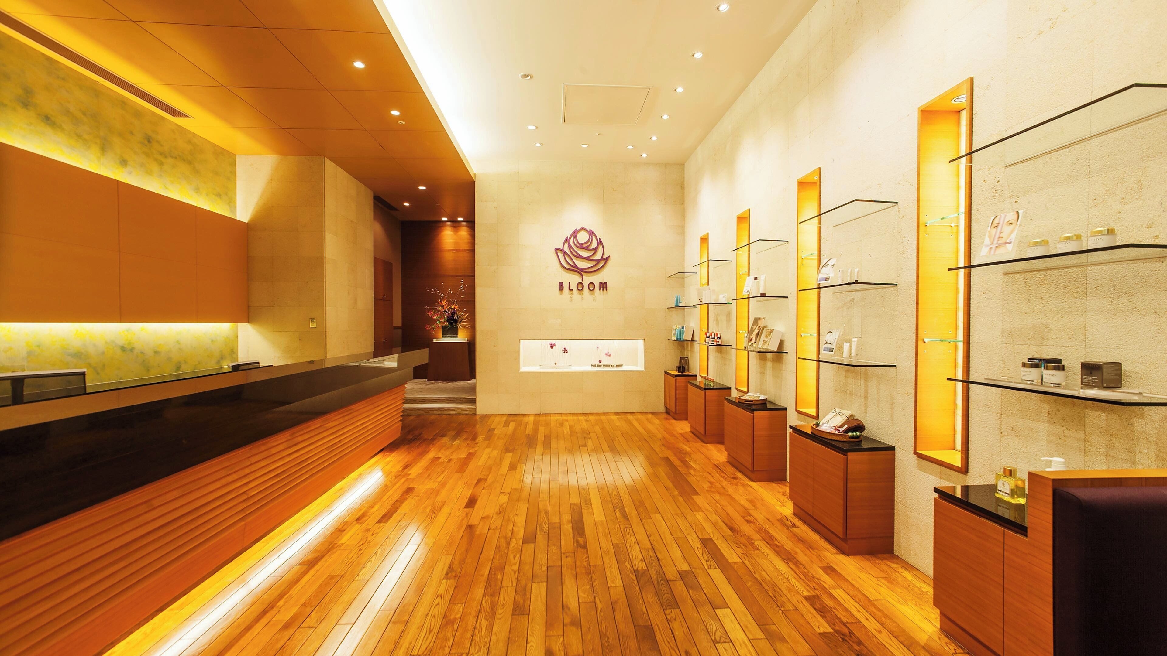 Un spa moderno con suelo de madera, un mostrador de recepción y estanterías con productos.
