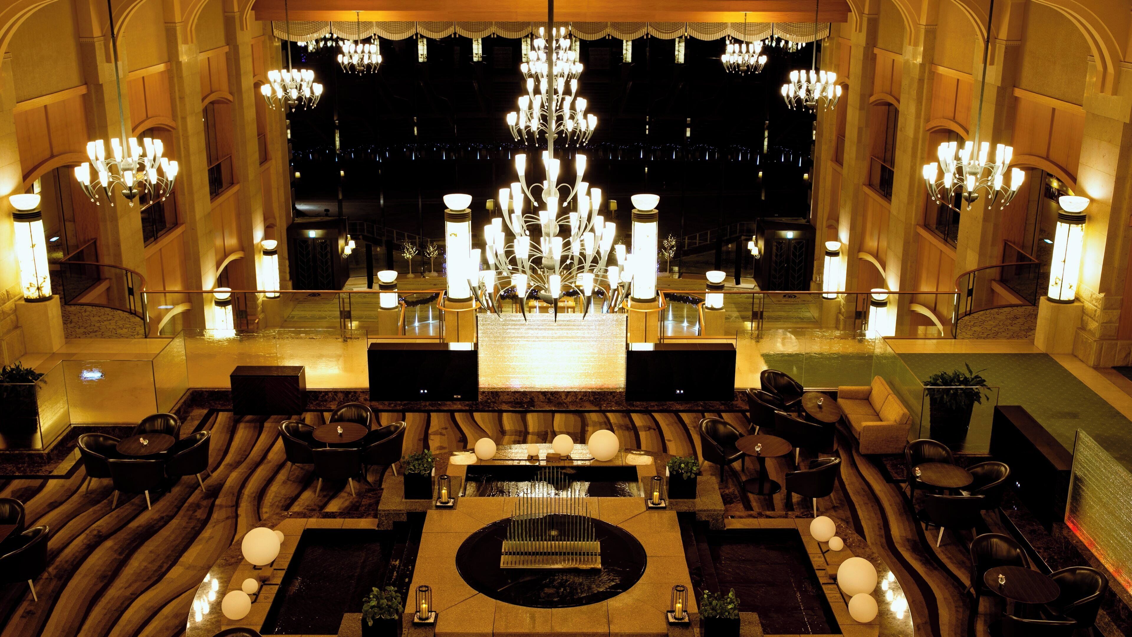 A grand lobby with a central fountain, multiple seating areas, and a large chandelier.