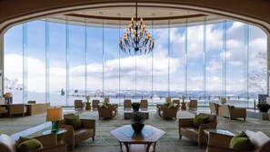 A spacious lobby with a large arched glass window offering a view of a snowy landscape and a bridge. - The Windsor Hotel Toya, Vignette Collection by IHG (Toyako)