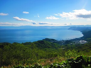 A coastal landscape with a view of the sea and a town nestled in the hills. - The Windsor Hotel Toya, Vignette Collection by IHG (Toyako)