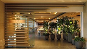 A modern hotel lobby with a wooden slatted entrance, a long reception desk, and several potted plants. - The Windsor Hotel Toya, Vignette Collection by IHG (Toyako)