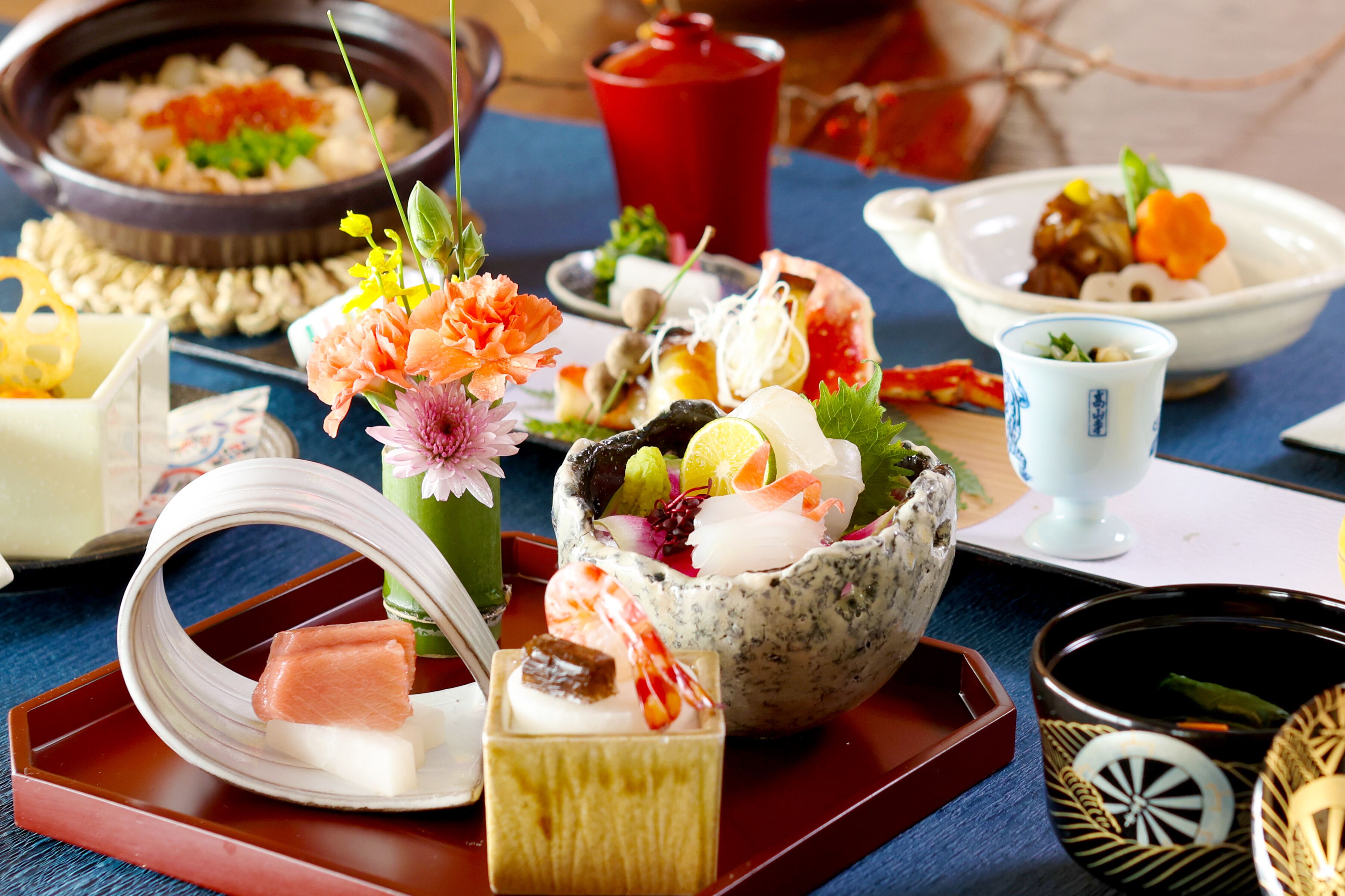 A variety of Japanese dishes and drinks on a table, including sushi, sashimi, and a bowl of assorted vegetables and fruits.