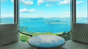 A view from a window with two patterned chairs facing a large body of water and distant mountains. - The Windsor Hotel Toya, Vignette Collection by IHG (Toyako)