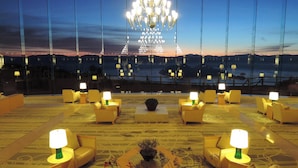 A hotel lobby with a large chandelier, multiple seating areas with lamps, and a view of a cityscape at dusk. - The Windsor Hotel Toya, Vignette Collection by IHG (Toyako)