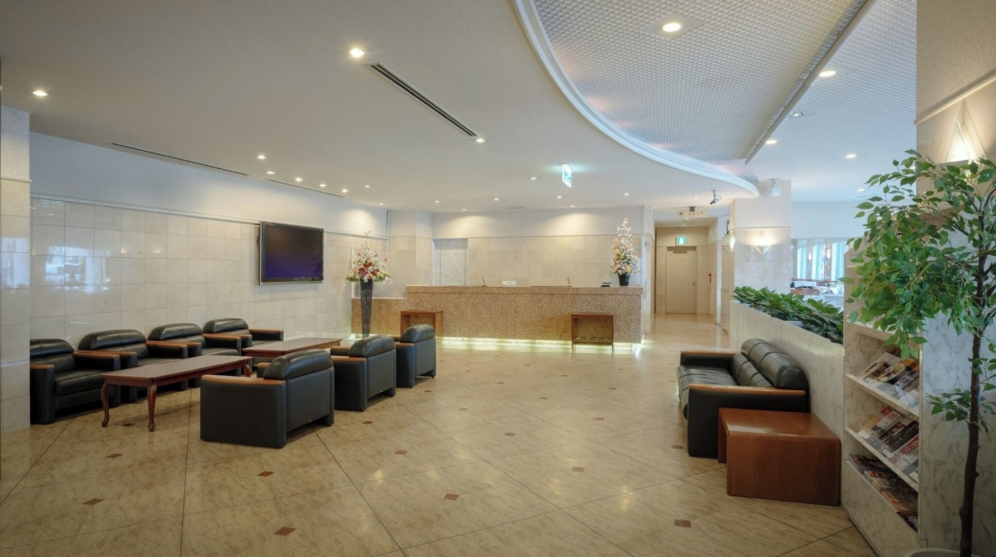 A modern reception area with a curved ceiling, a reception desk, seating arrangements, and a plant display.