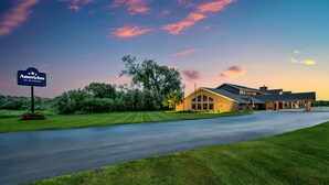 A hotel with a signboard, a well-maintained lawn, and a building with a stone facade. - AmericInn by Wyndham Baudette (Baudette)