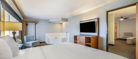A hotel room with a large bed, a desk, a chair, a television, and a bathroom.