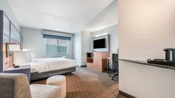 Una habitación de hotel con una cama, un escritorio, una silla, un televisor y un microondas.