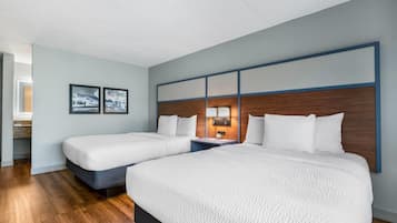 Une chambre d’hôtel avec deux lits, une table de chevet avec une lampe et des tableaux encadrés au mur.