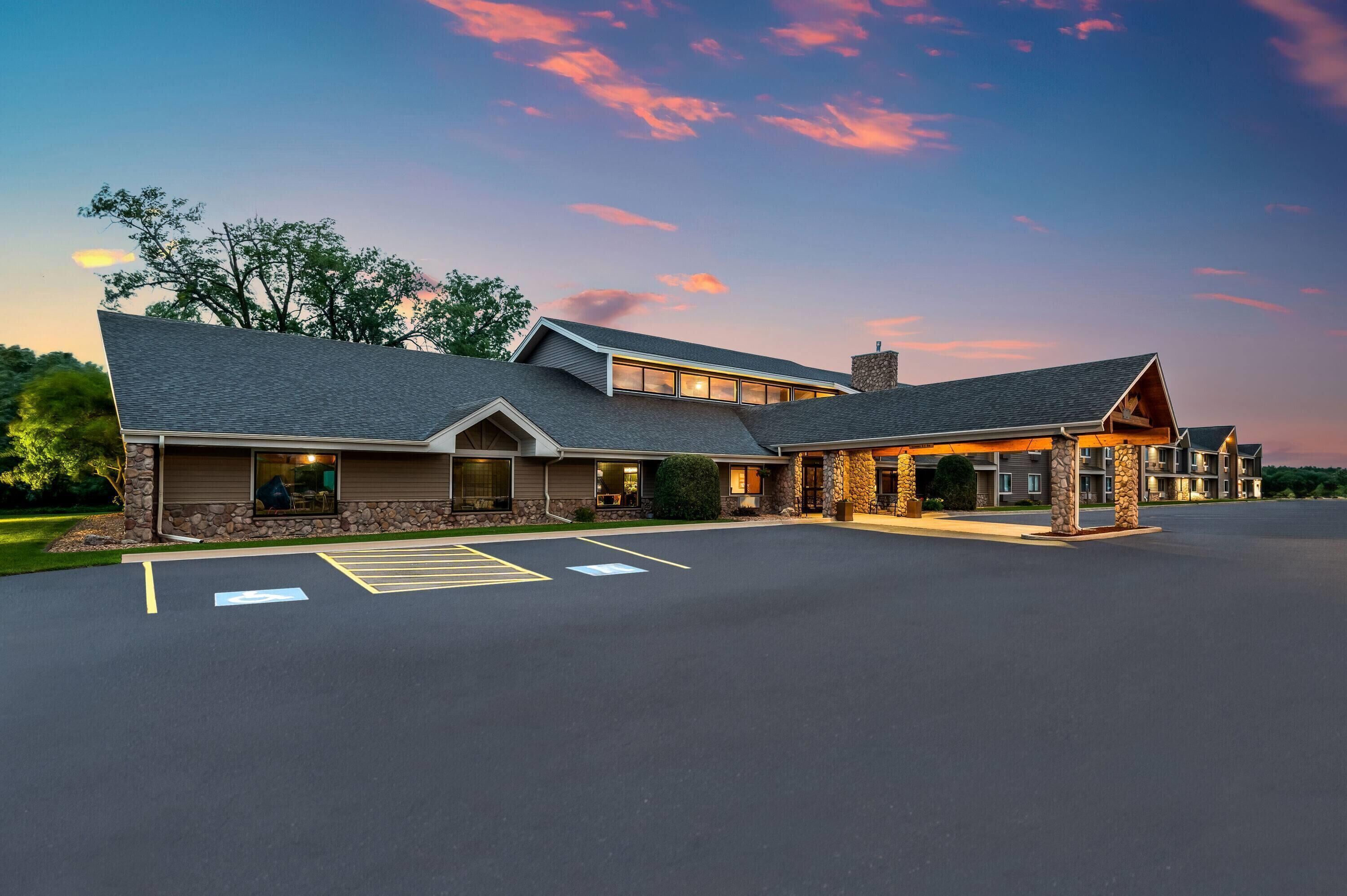 A hotel with a stone facade, multiple windows, and a parking lot.
