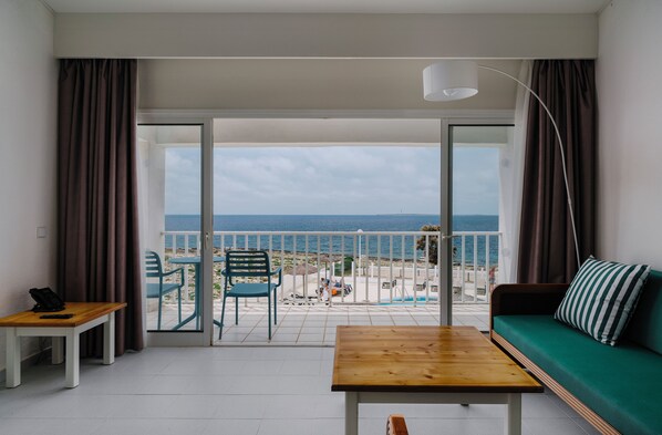 Un balcone con vista sul mare, un divano verde, un tavolo di legno e una sedia.