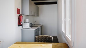 A compact kitchen with a microwave, sink, and a fire extinguisher on the wall. - Aluasun Far Menorca (Sant Lluis)