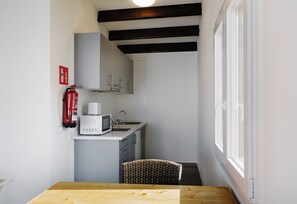 Una cucina compatta con forno a microonde, lavello e estintore a parete.