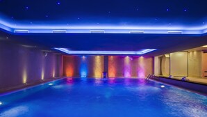 A large indoor swimming pool with a modern design, featuring a blue-lit ceiling and walls, and a clear view of the pool's length. -  Movenpick hotel Sarajevo (Sarajevo)