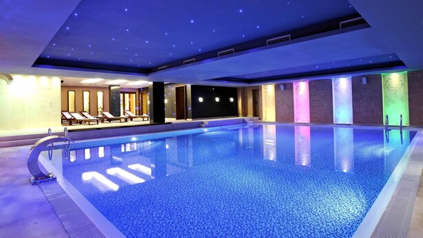 A modern indoor swimming pool with a starry ceiling, lounge chairs, and a tiled floor. - Movenpick hotel Sarajevo (Sarajevo)