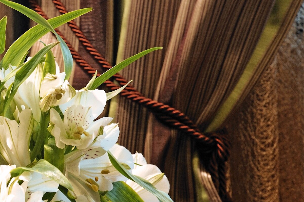 A close-up of white flowers with green leaves against a background of brown striped fabric.
