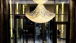 A lobby with a geometric patterned floor, a revolving door, and a chandelier. - Movenpick hotel Sarajevo (Sarajevo)
