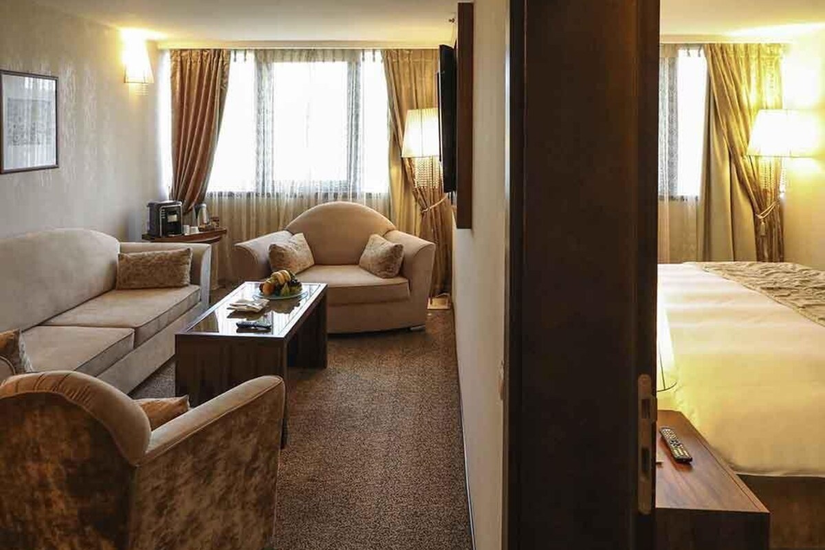 A hotel room with a bed, two sofas, a coffee table, and a TV.