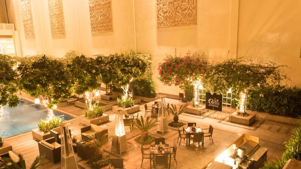 An indoor patio area with seating, a pool, and decorative plants. - Jaipur Marriott Hotel (Jaipur)