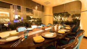 A conference room with a long table, chairs, and a glass partition.