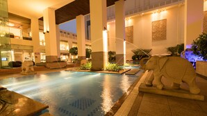 A pool area with a statue of an elephant, stone benches, and a fountain. - Jaipur Marriott Hotel (Jaipur)