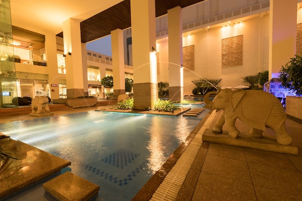 A pool area with a statue of an elephant, stone benches, and a fountain. - Jaipur Marriott Hotel (Jaipur)