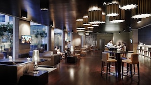 A modern hotel lobby with a bar area, seating arrangements, and a television screen. - Jaipur Marriott Hotel (Jaipur)