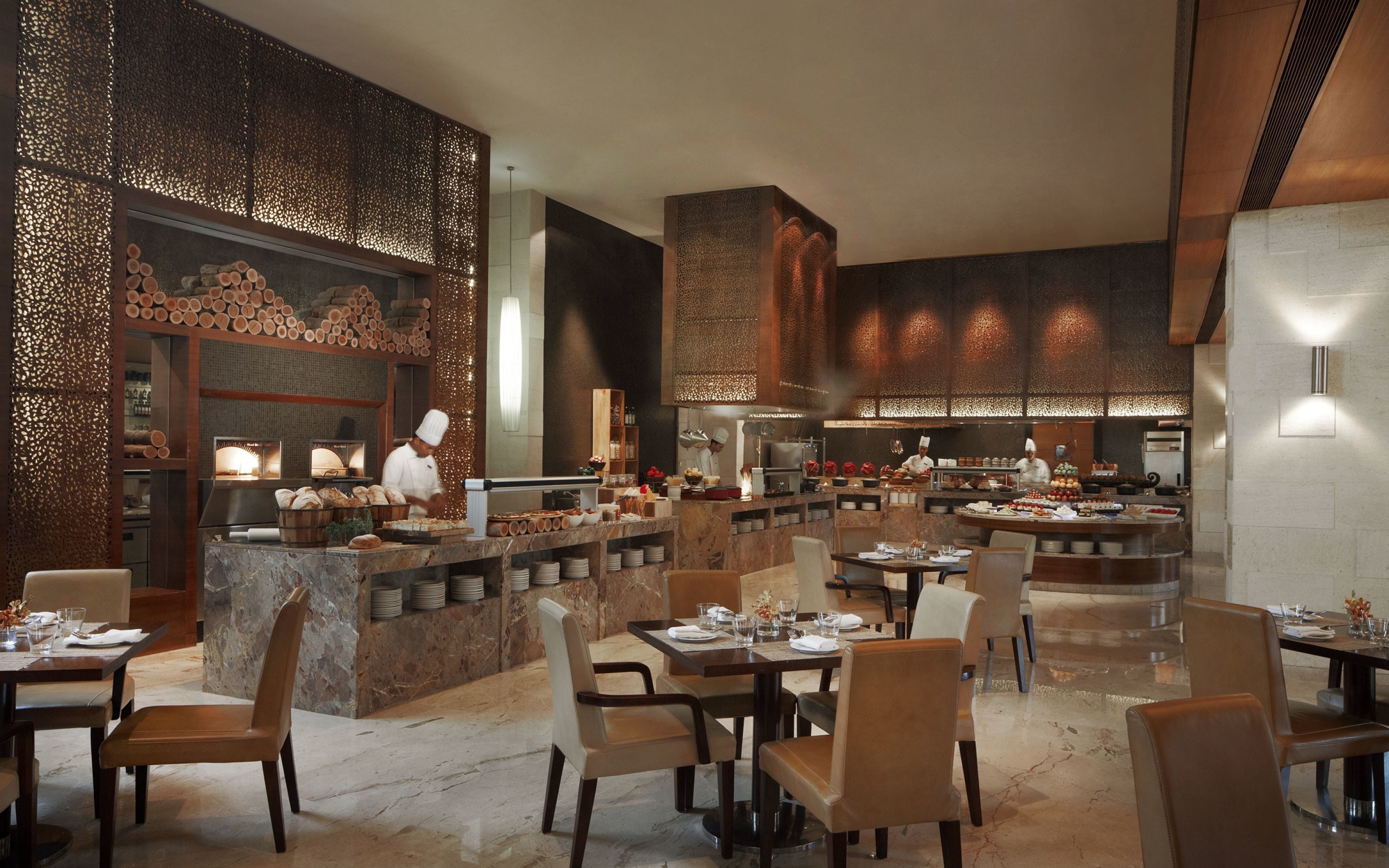 Un restaurante moderno con suelo de mármol, muebles de madera y una barra central.