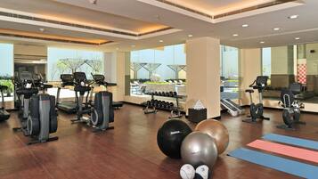 Uma academia com esteiras, elípticos e bolas de exercício.